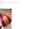 A hand holds a vibrant rainbow colored synthetic hair extension clip-in.