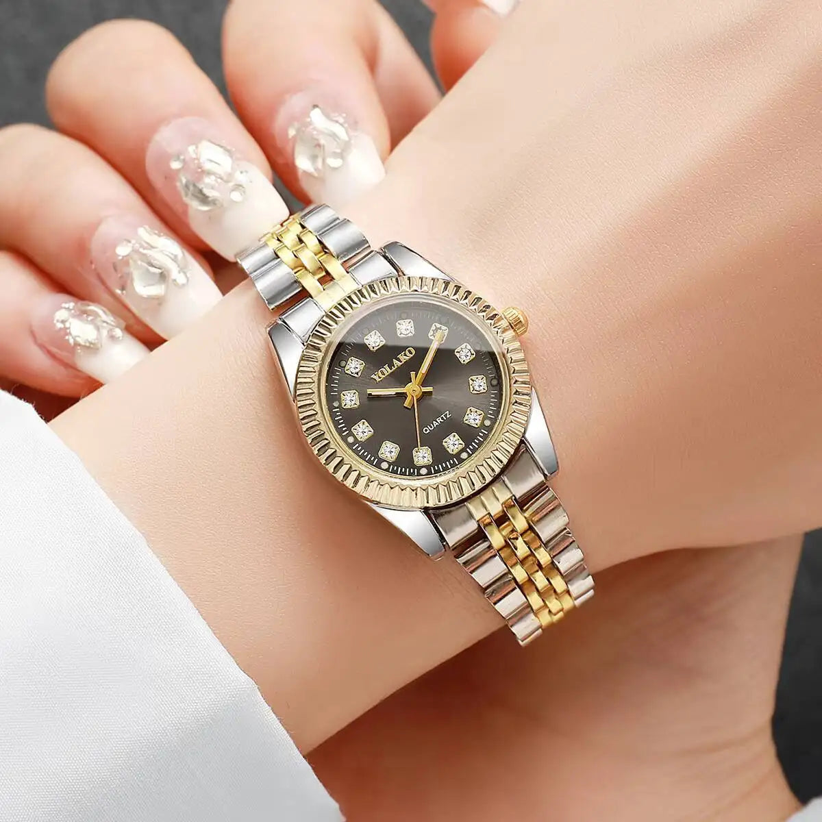 A silver and gold rhinestone quartz wristwatch is worn on a person's wrist.