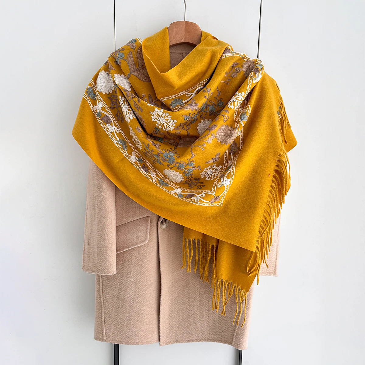 A mustard yellow luxury floral scarf draped over a beige blazer.