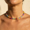 Nahaufnahme des Halses und der Brust einer Frau mit einem farbenfrohen Perlen-Choker-Halsband.