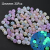 A collection of iridescent glow-in-the-dark acrylic beads in various shades of pink, purple, and blue.