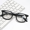 A pair of black-framed multifocal reading glasses resting on a white laptop keyboard.