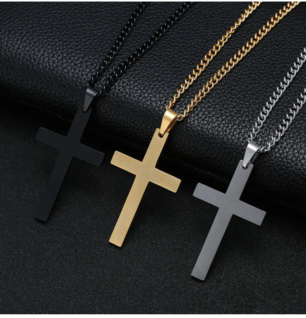 Drei silber- und goldfarbene Kreuz-Anhänger aus Edelstahl auf schwarzem Untergrund.