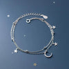 Sterling silver double heart charm bracelet displayed on a dark blue background with small silver stars.