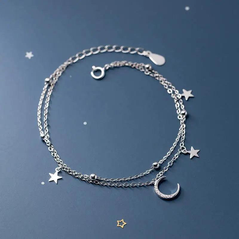 Sterling silver double heart charm bracelet displayed on a dark blue background with small silver stars.