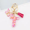 Alphabet letter acrylic keychain featuring a pink butterfly charm and a magenta tassel