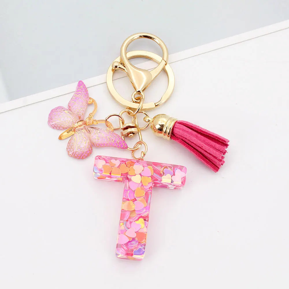 Alphabet letter acrylic keychain featuring a pink butterfly charm and a magenta tassel