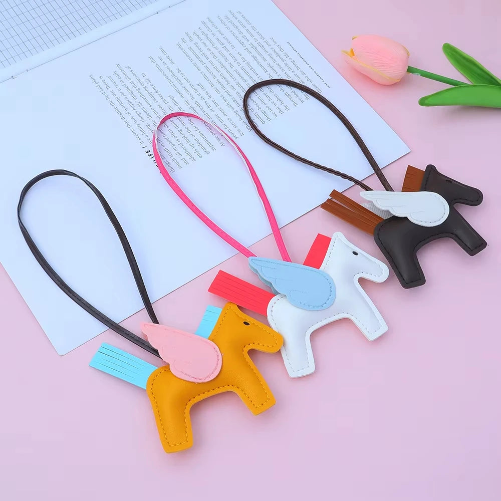 A collection of elegant horse pendant charms in various colors including pink, black, yellow, and white, displayed on a light