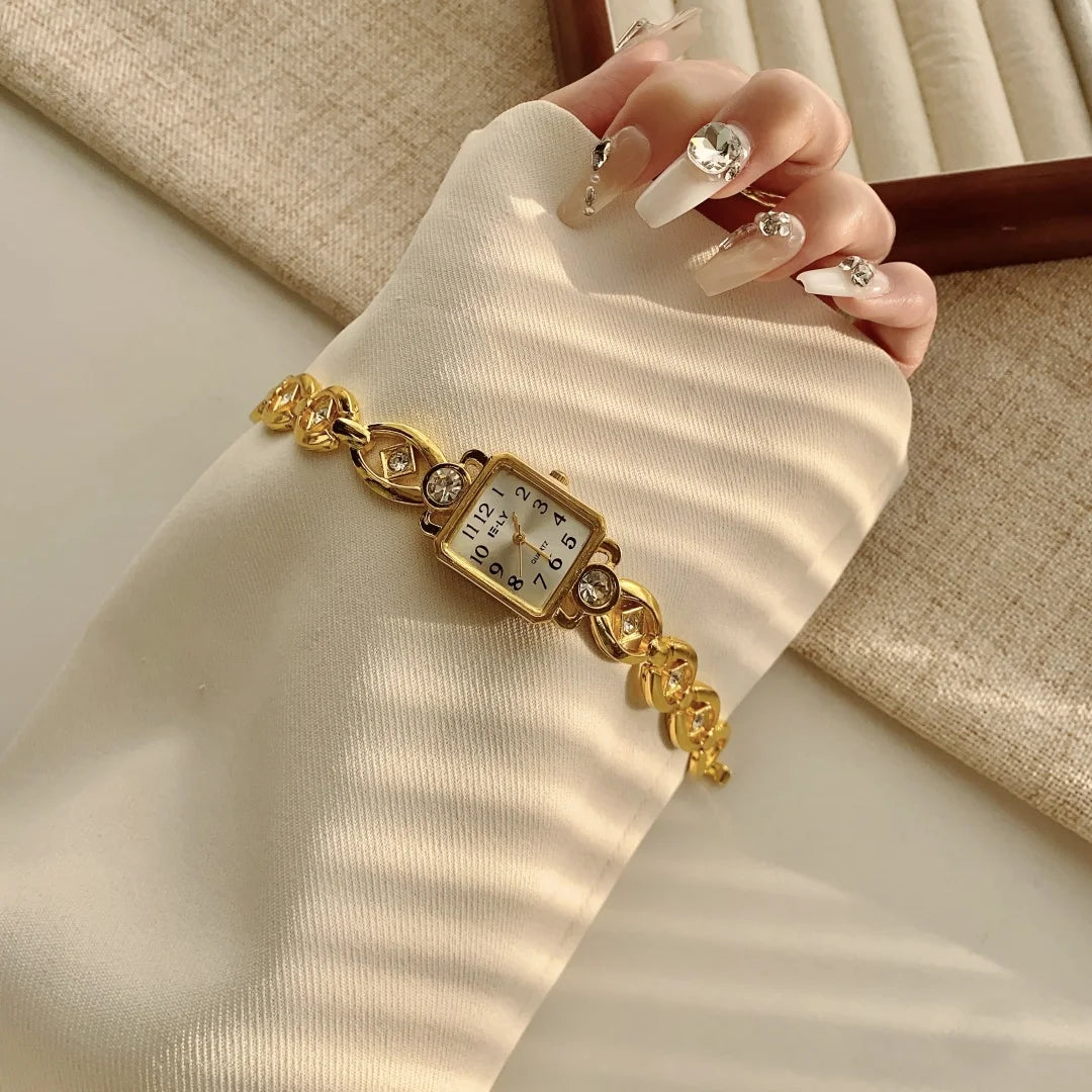 A close-up of a hand wearing an elegant gold quartz fashion wristwatch on a light-colored sleeve.