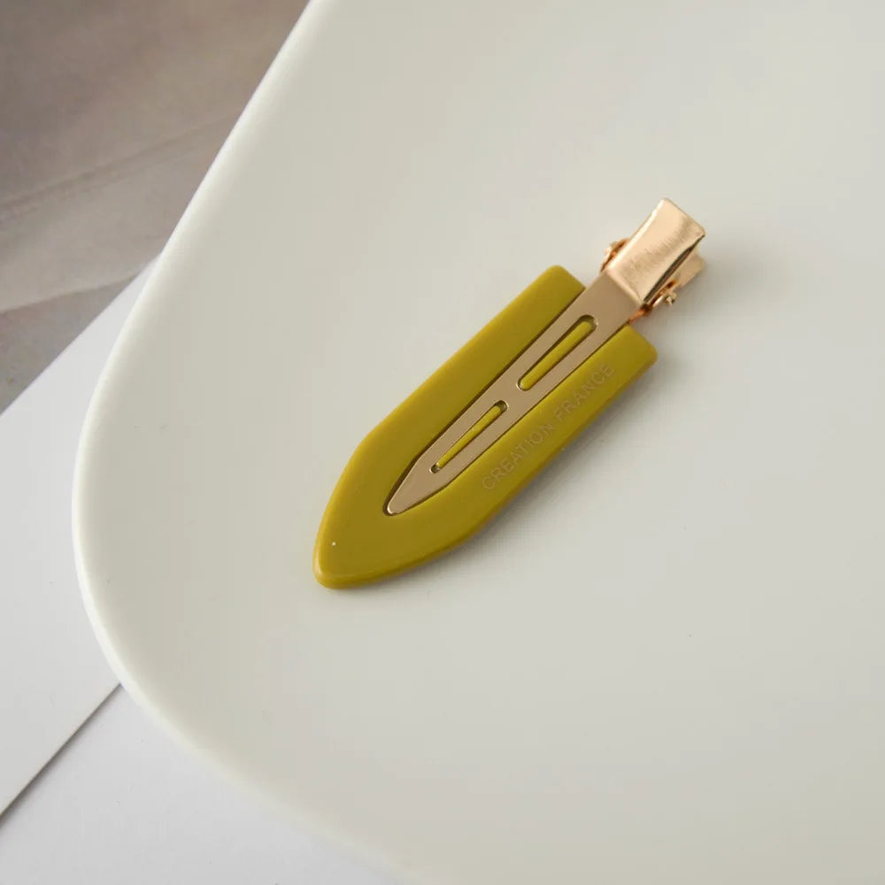 Une pince à cheveux en or imprimée, vert lime, repose sur une assiette blanche.