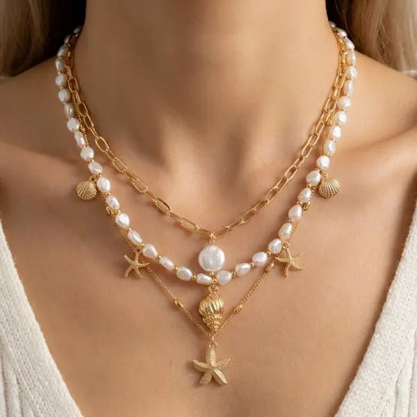 Gold layered necklace featuring white pearls and a starfish pendant