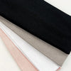 A stack of four knitted hair bands in black, gray, white, and pink shades.