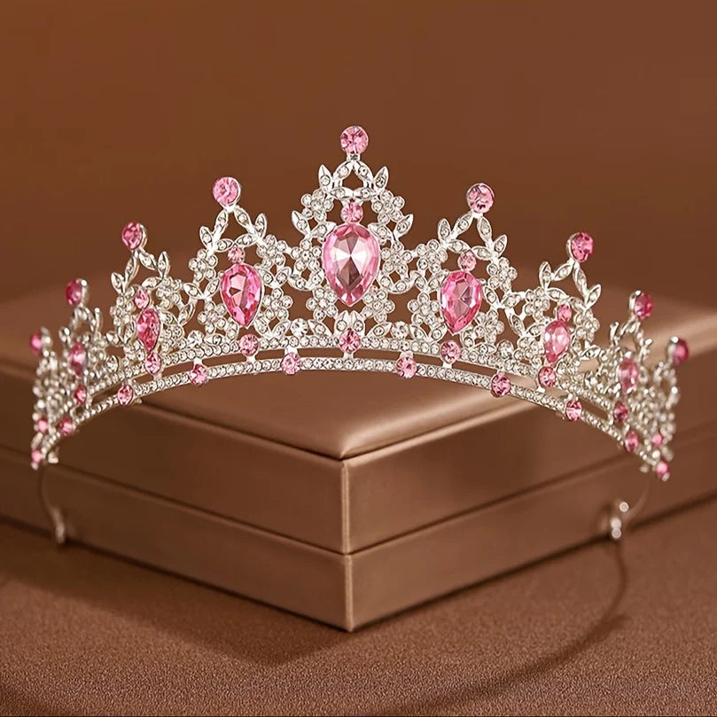 Diadema de tiara de cristal rosa brillante y transparente con detalles florales, mostrada en una caja marrón.