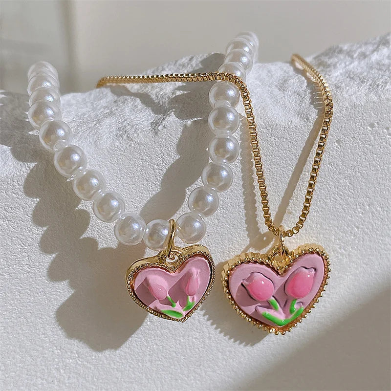 A delicate necklace featuring white pearls and a gold chain with a pink crystal heart pendant.