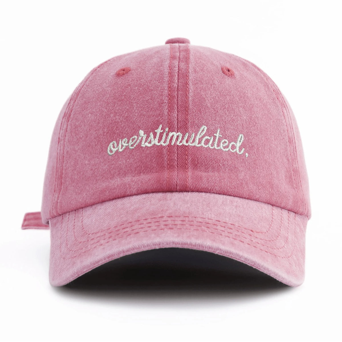 A pink washed baseball cap embroidered with the word overstimulated