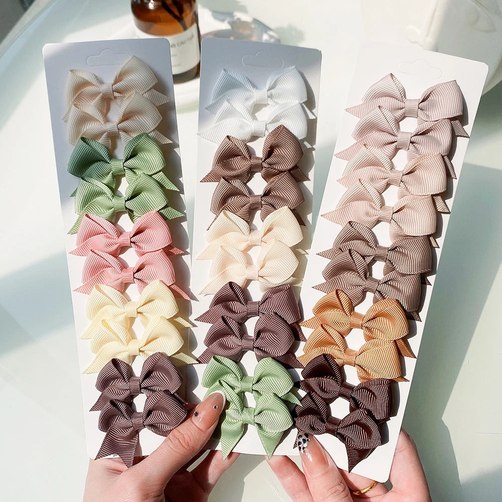 Un juego de pinzas para el pelo con lazos de colores sólidos infantiles en tonos rosa, verde, beige y marrón.