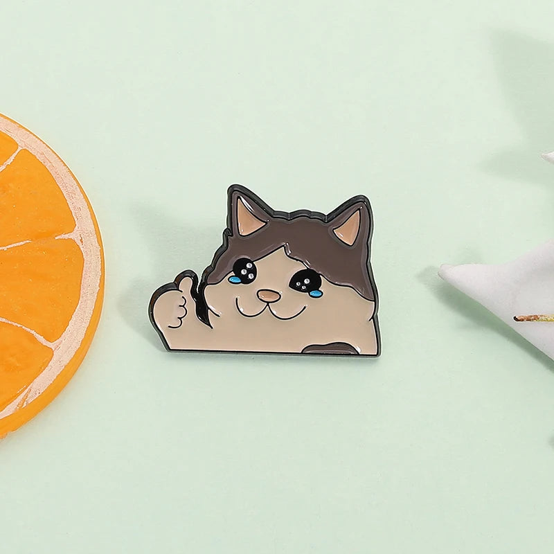 A cute enamel pin of a cat with blue eyes and a smiling expression.