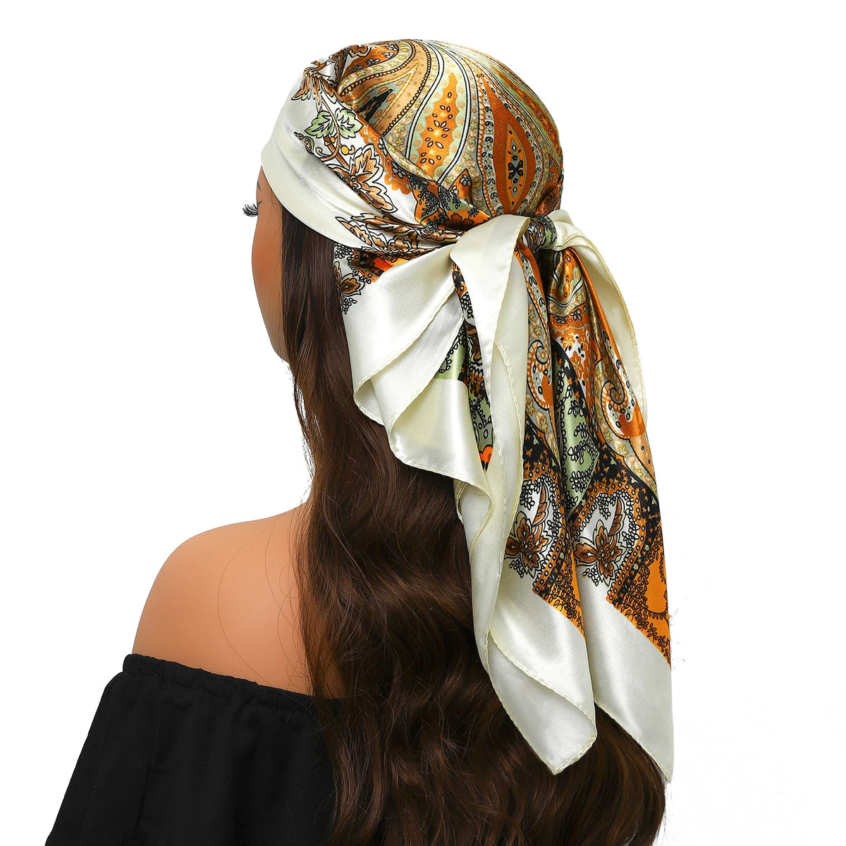 Eine Frau trägt einen luxuriösen Seidenschal mit orange-cremefarbigem Paisley-Muster, gebunden um ihr Haar.