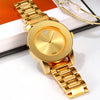 Reloj de cuarzo dorado con esfera redonda y joya brillante, sobre una superficie blanca.