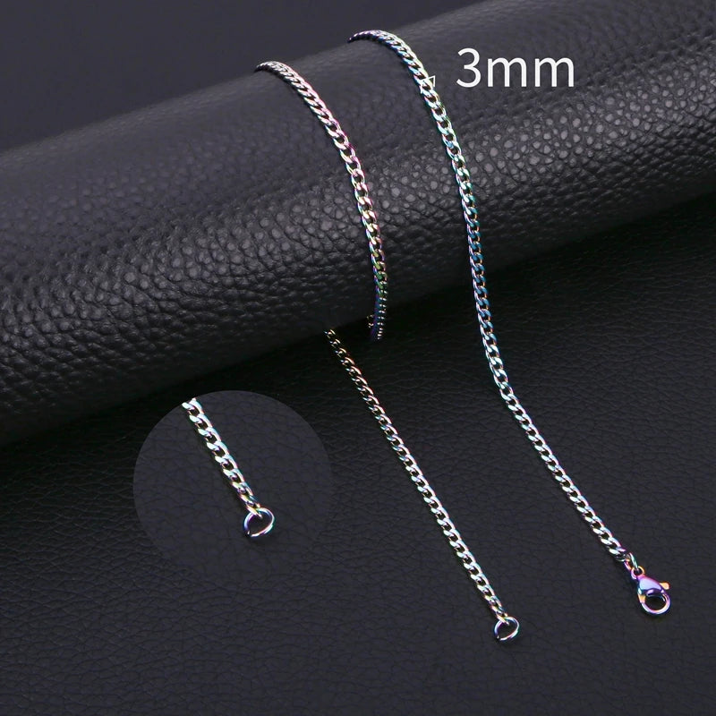 A close-up of a 3mm stainless steel Cuban link necklace in iridescent colors displayed on a black surface.