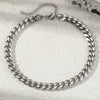 A silver multi-chain stainless steel anklet laid flat on a light, textured surface.