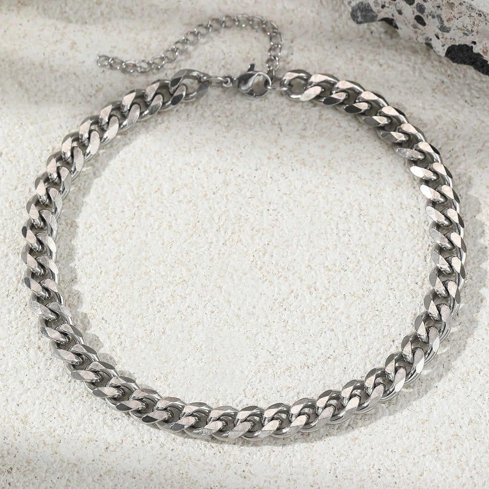 A silver multi-chain stainless steel anklet laid flat on a light, textured surface.