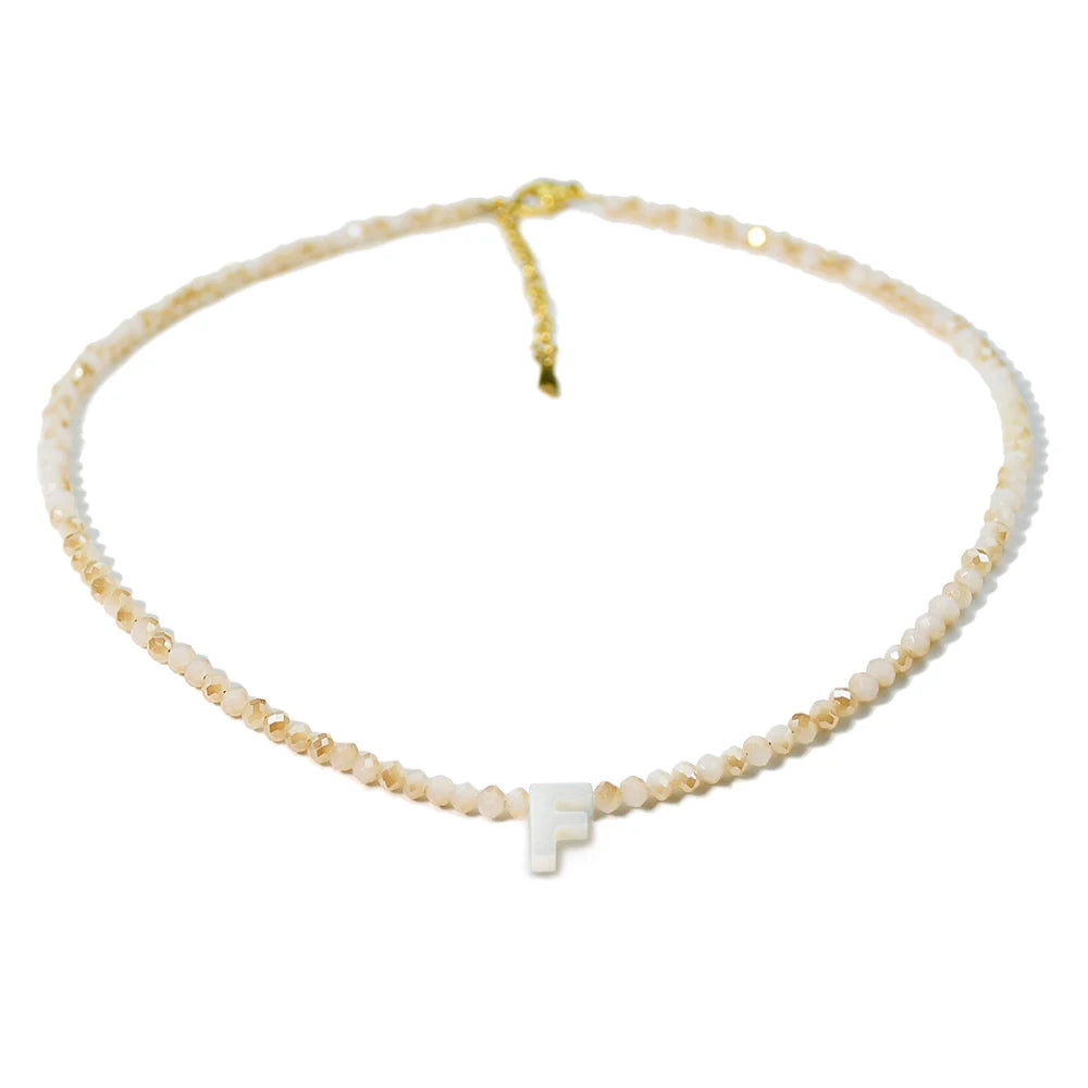 A delicate necklace made of mother of pearl beads with crystal accents and a silver initial charm.