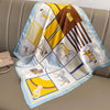 A colorful silk scarf featuring African animal motifs and geometric patterns draped on a beige sofa.