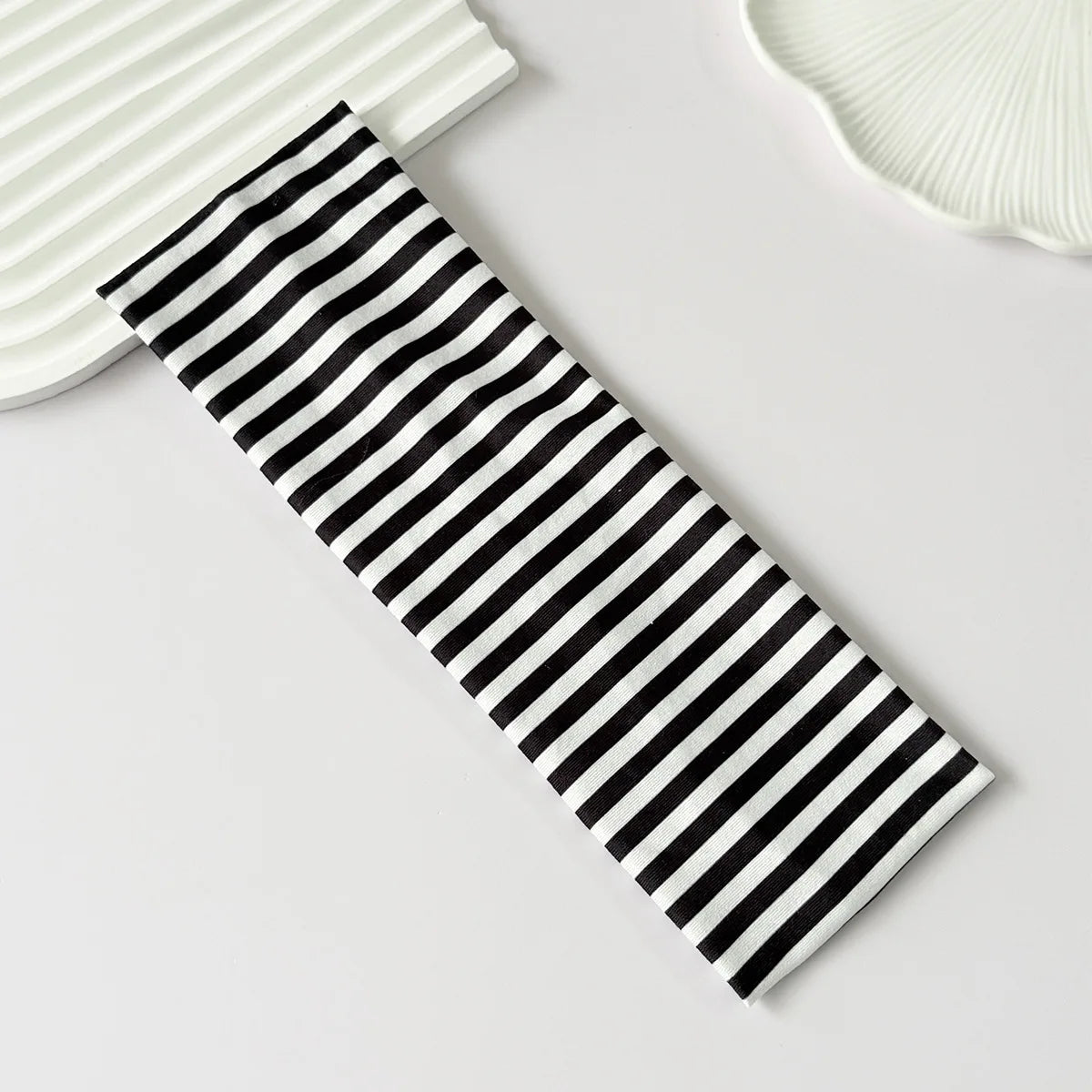 Un élastique pour cheveux rayé noir et blanc posé sur une surface blanche.