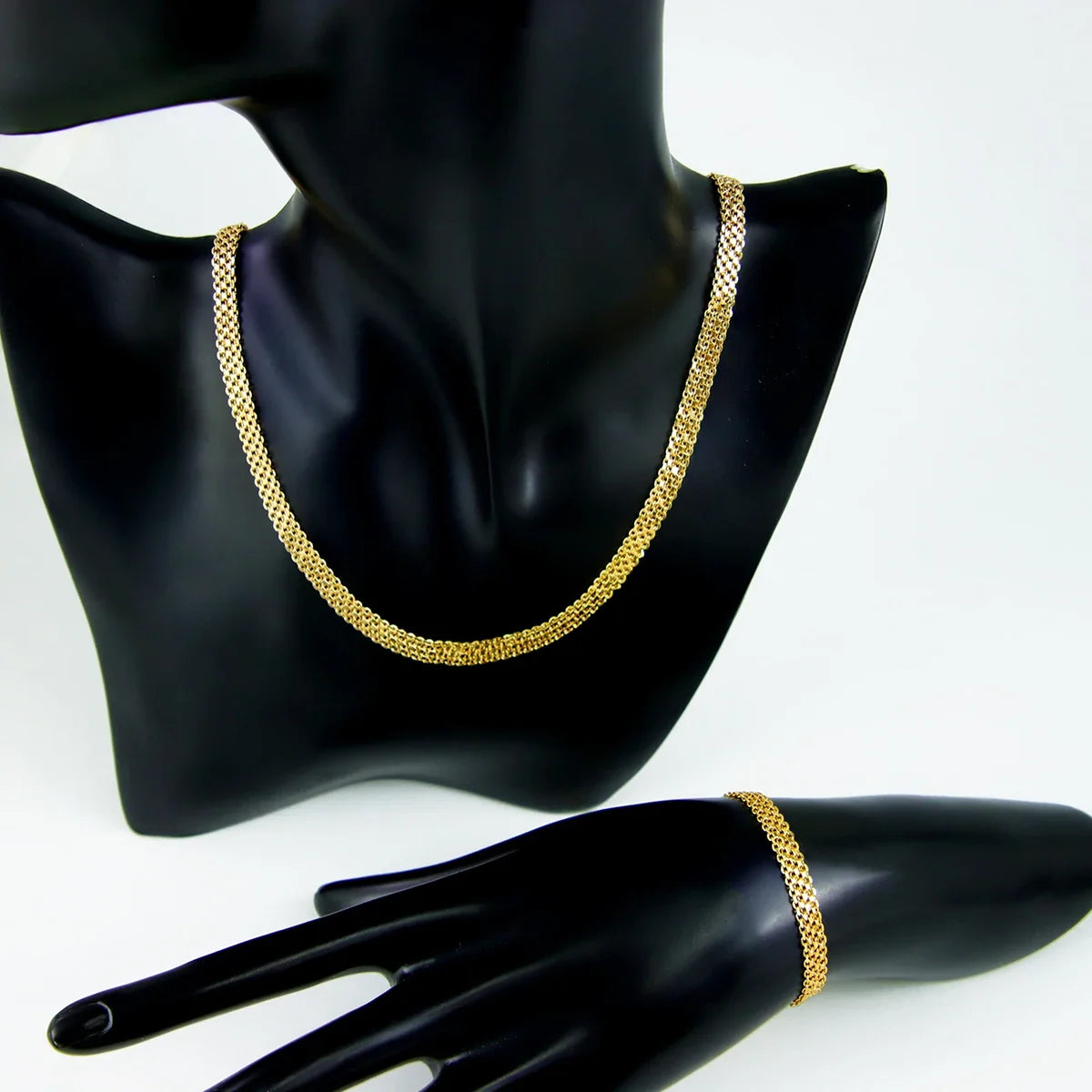 A close-up of an elegant gold plated chain necklace displayed on a black mannequin neck.