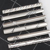 A collection of silver metal tie clips displayed diagonally on a black plaid fabric background.