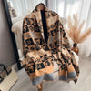 A beige and black plaid cashmere scarf draped over a white chair in a bright room.
