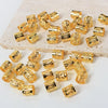 A collection of small, gold-colored, textured metal hair rings and clips scattered on a light surface.
