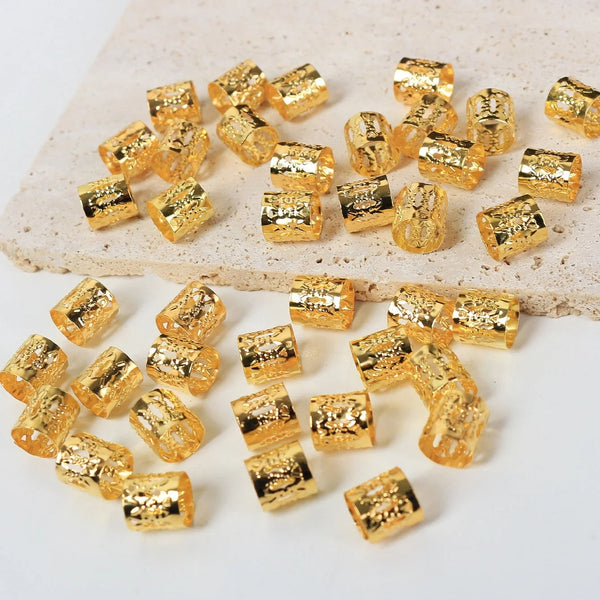A collection of small, gold-colored, textured metal hair rings and clips scattered on a light surface.