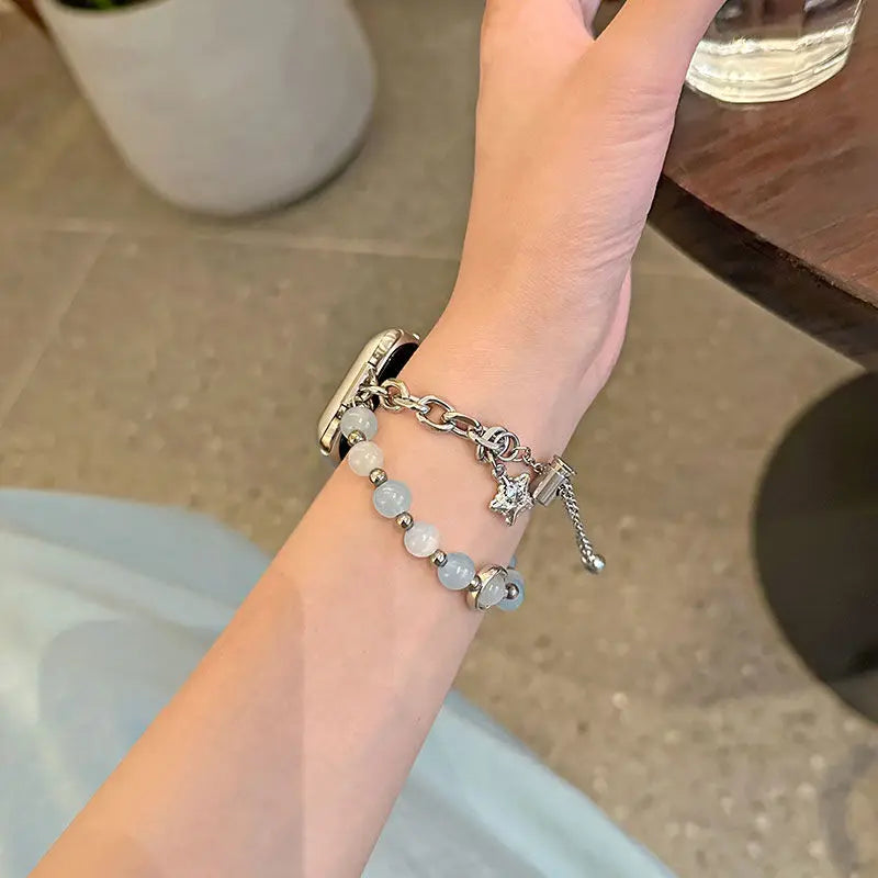 A close-up of a hand wearing a handmade transparent blue double chain watch strap.