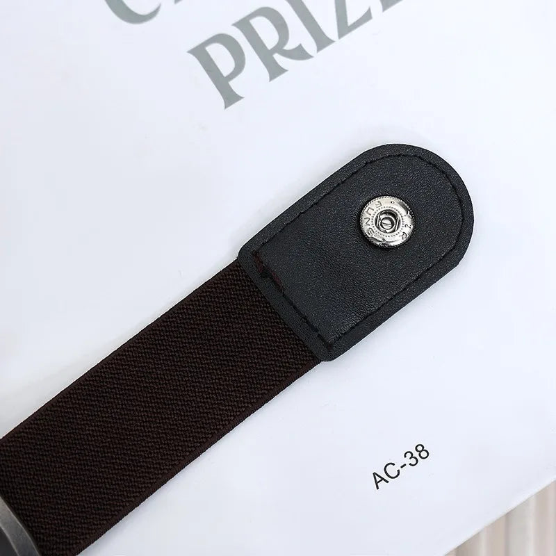 A close-up of a black elastic casual belt with a silver buckle resting on a white surface.