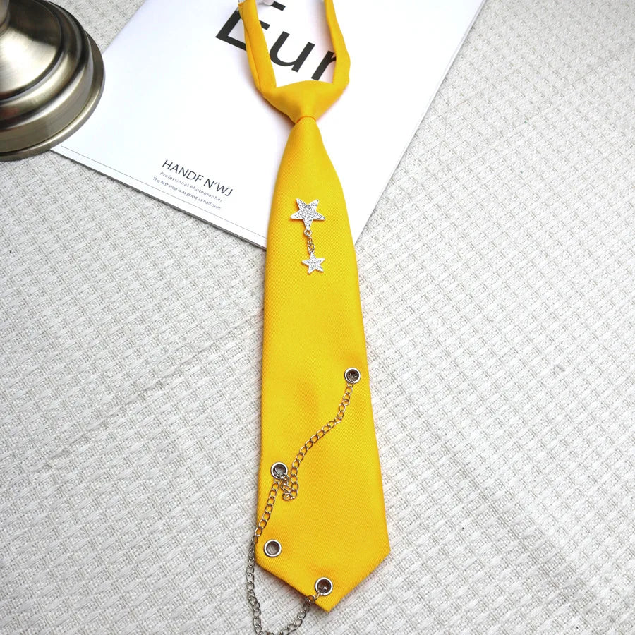 A bright yellow tie featuring a silver chain star decoration, displayed on a white card.