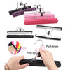 Various colored metal hair extension holders and a black holder being used to push down a wooden wig.
