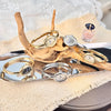 A collection of elegant gold-toned quartz watches and rings displayed on a wooden branch and a reflective surface.