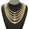 A close-up of a gold Cuban link chain necklace displayed on a black display stand.
