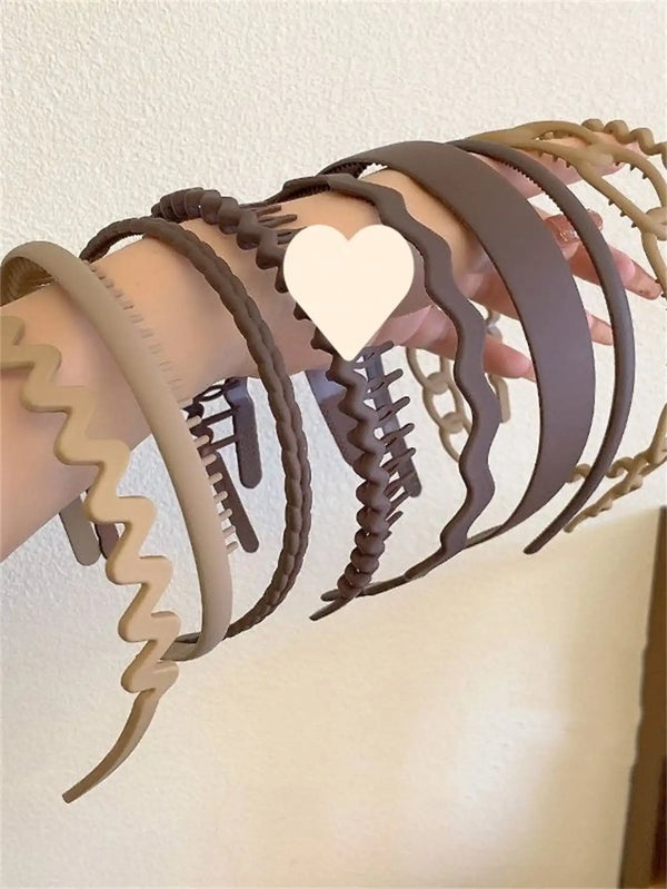 A collection of various brown and beige hair accessories including headbands and hair ties displayed on a hand.