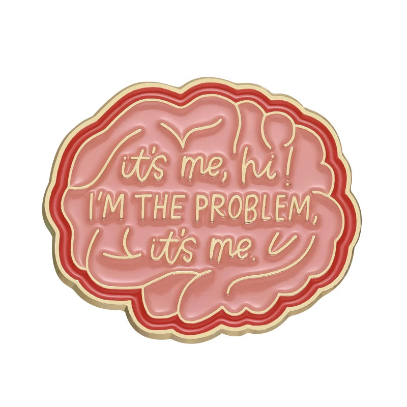 A pink quote enamel pin shaped like a speech bubble with the text It's me hi I'm the problem It's me