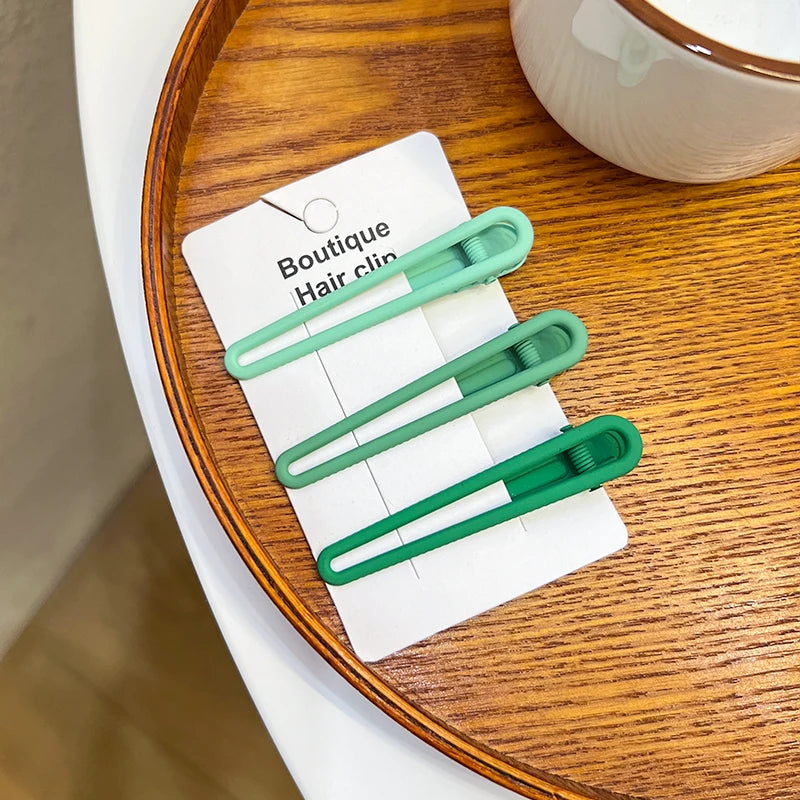 A set of vintage frosted geometry hair clips in a light green color displayed on a wooden tray.