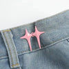 A pair of pink star-shaped decorative waist buckle buttons attached to a denim fabric.