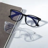 A pair of vintage square anti-blue light eyeglasses with dark frames and blue lenses resting on a gray surface.