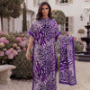 A woman wearing a purple and white leopard zebra print maxi kaftan standing outdoors in a garden setting.