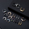 A collection of magnetic stainless steel septum rings in various styles and finishes displayed on a black surface.