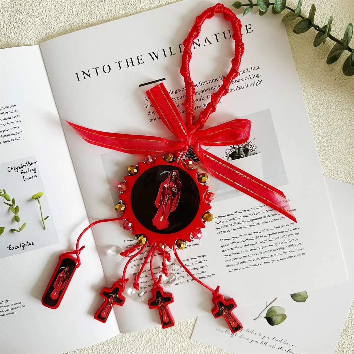 A red wooden cross pendant with a ribbon is displayed on an open book page.