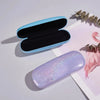 Une boîte de rangement à paillettes bleu clair et une bouteille de vernis à ongles violet sont présentées sur du papier blanc