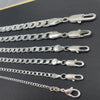 A collection of silver geometric face chain necklaces displayed on a dark background.